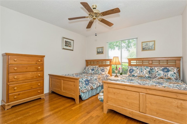 bedroom featuring hardwood / wood-style flooring, ceiling fan, and a textured ceiling