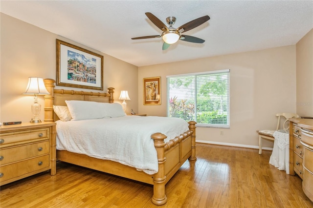 bedroom featuring ceiling fan, light hardwood / wood-style floors, and a textured ceiling