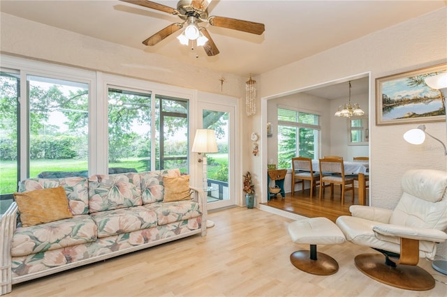 living room featuring ceiling fan with notable chandelier and wood-type flooring