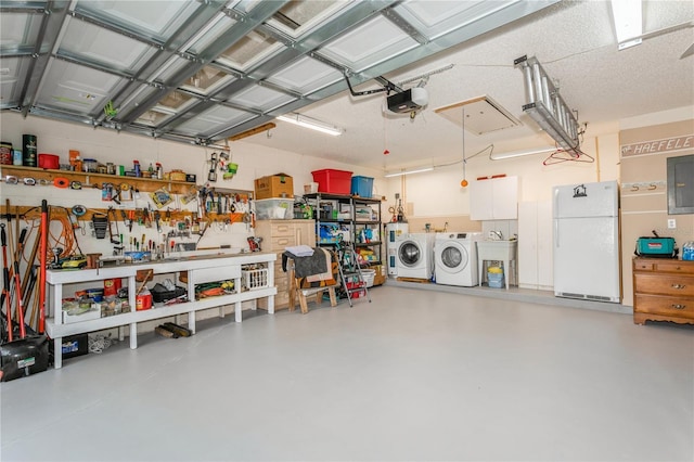 garage with a workshop area, a garage door opener, white refrigerator, sink, and washing machine and clothes dryer