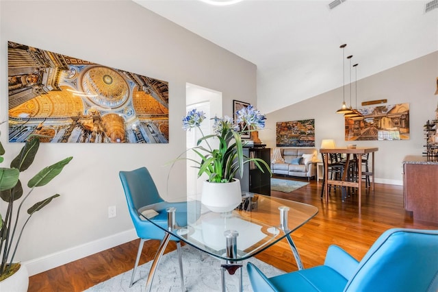 dining area featuring wood-type flooring and vaulted ceiling