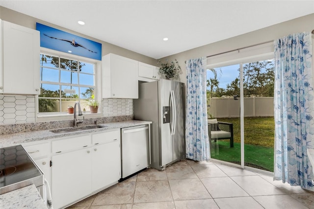 kitchen featuring white cabinetry, sink, stainless steel appliances, light stone counters, and decorative backsplash