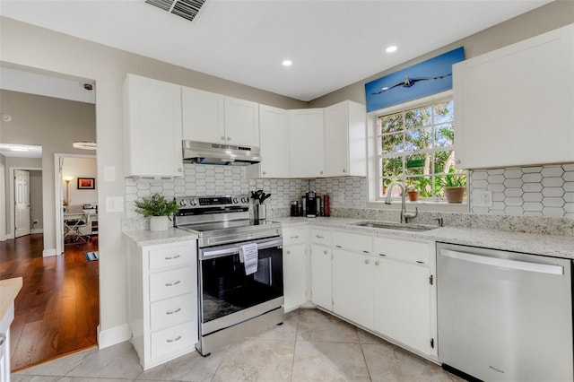 kitchen with sink, white cabinets, stainless steel appliances, and light tile patterned floors