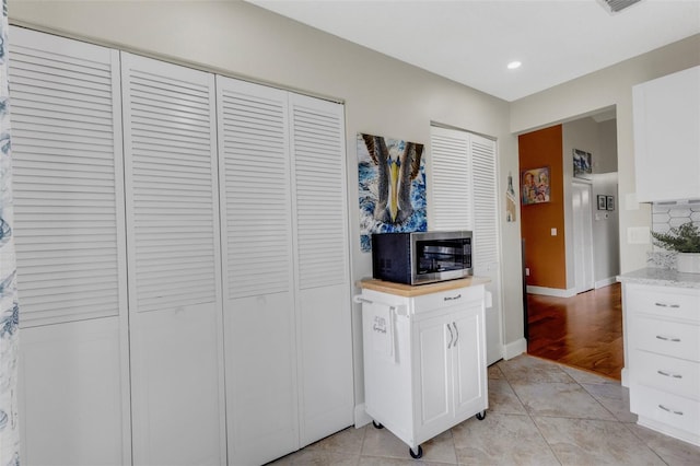 kitchen with white cabinets, backsplash, and light tile patterned flooring