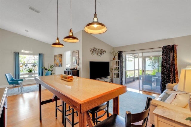 dining space featuring high vaulted ceiling and light hardwood / wood-style flooring