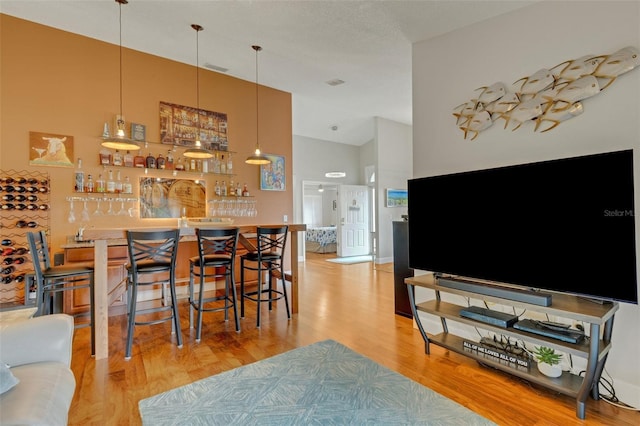 dining room featuring a high ceiling, light hardwood / wood-style flooring, and bar