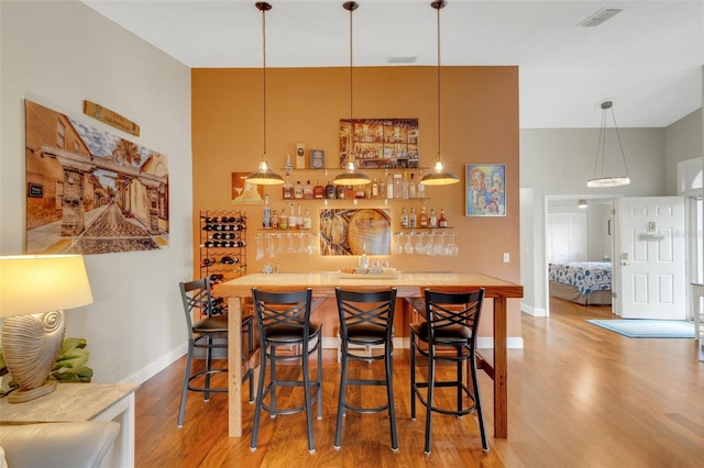 bar featuring decorative light fixtures and light hardwood / wood-style flooring