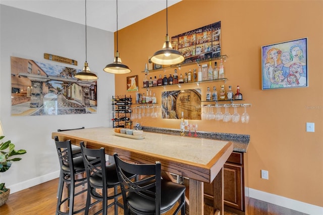 bar featuring hardwood / wood-style floors and decorative light fixtures