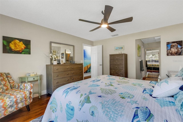 bedroom with ceiling fan, dark hardwood / wood-style floors, a textured ceiling, and connected bathroom