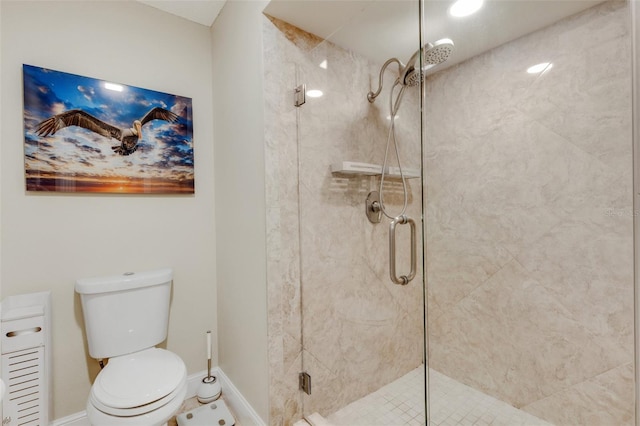 bathroom featuring a shower with shower door and toilet