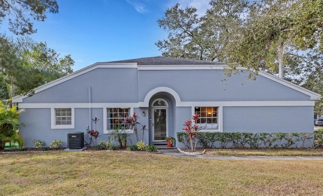 view of front of house with central AC unit, a front lawn, and stucco siding