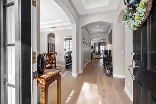 foyer with a tray ceiling, light hardwood / wood-style flooring, and ornamental molding