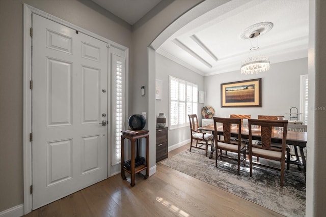 foyer featuring hardwood / wood-style flooring, a notable chandelier, and ornamental molding