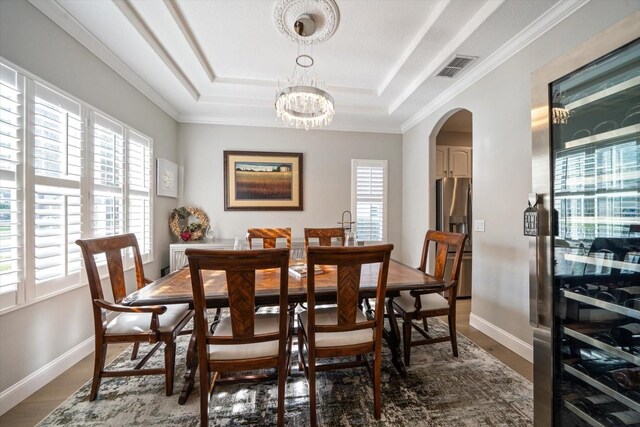 dining space featuring a raised ceiling, plenty of natural light, and a notable chandelier