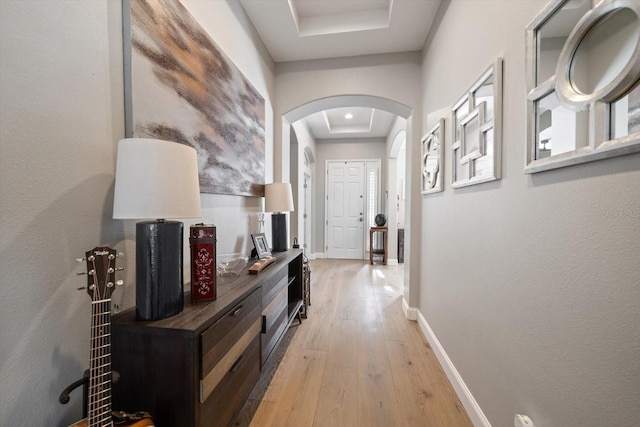 hall with light hardwood / wood-style floors and a raised ceiling