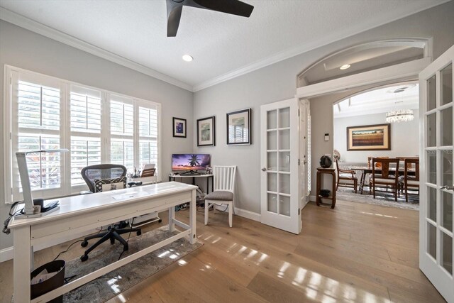 office with ceiling fan with notable chandelier, crown molding, light hardwood / wood-style flooring, and french doors