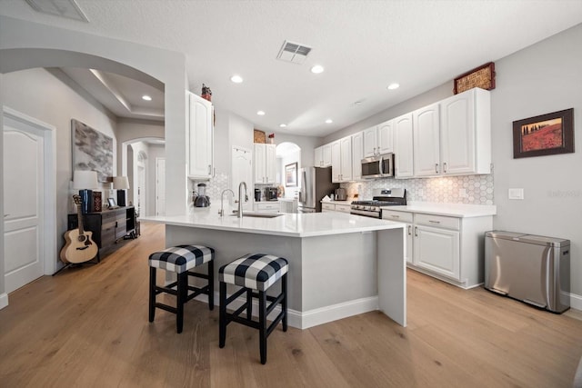 kitchen featuring a breakfast bar, white cabinets, sink, light wood-type flooring, and stainless steel appliances