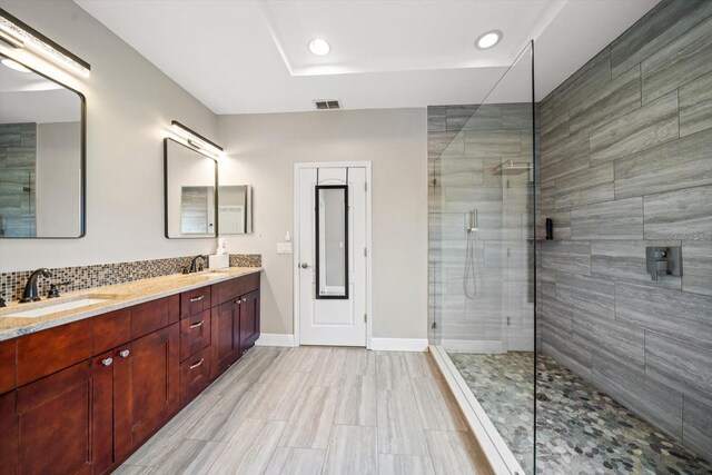 bathroom with vanity, a shower with shower door, and backsplash