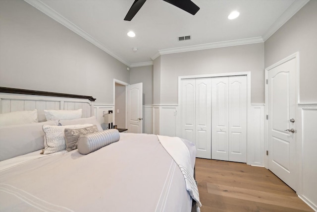 bedroom with a closet, light hardwood / wood-style flooring, ceiling fan, and ornamental molding