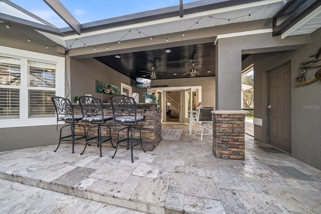 view of patio featuring ceiling fan and a bar