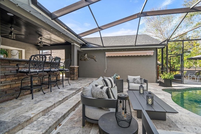 view of patio / terrace with an outdoor hangout area, ceiling fan, a bar, and glass enclosure