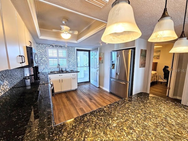 kitchen featuring a tray ceiling, white cabinetry, decorative light fixtures, and stainless steel refrigerator with ice dispenser