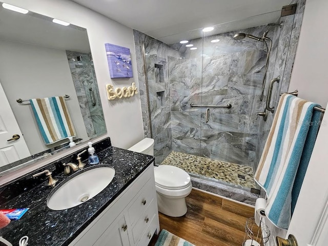 bathroom featuring wood-type flooring, vanity, toilet, and walk in shower