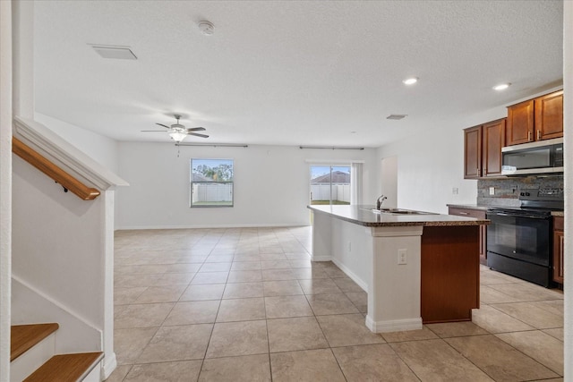 kitchen featuring electric range, sink, ceiling fan, an island with sink, and light tile patterned floors