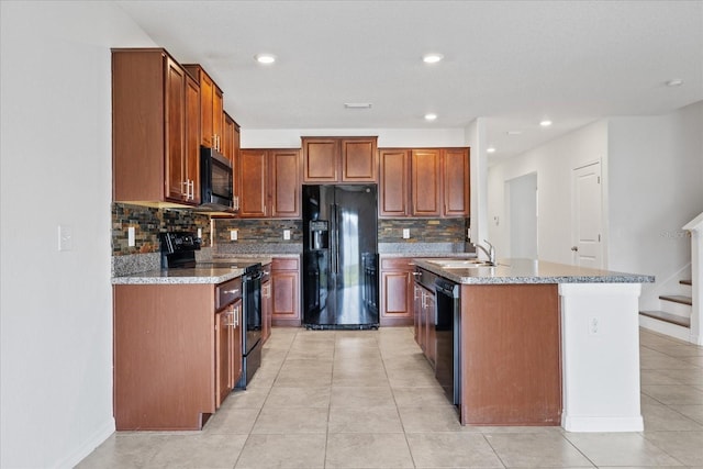 kitchen featuring black appliances, backsplash, sink, and a kitchen island with sink