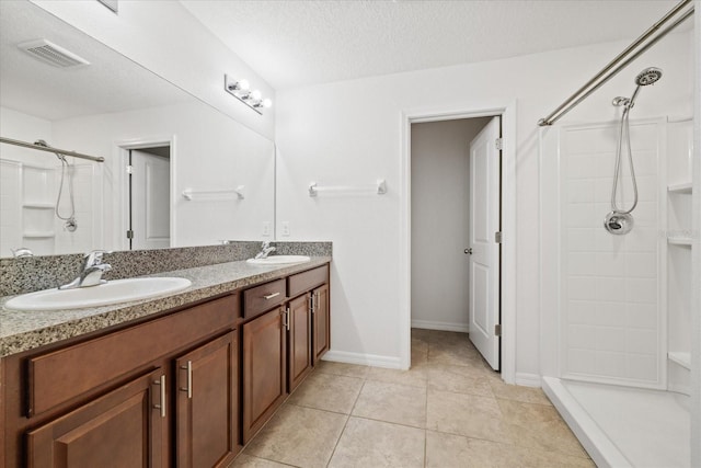 bathroom featuring a textured ceiling, vanity, tile patterned floors, and walk in shower