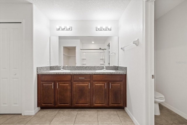 bathroom with walk in shower, a textured ceiling, vanity, tile patterned flooring, and toilet