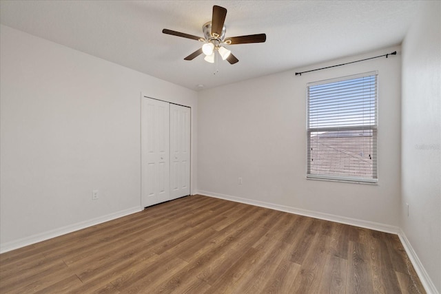 unfurnished bedroom featuring dark hardwood / wood-style flooring, ceiling fan, a closet, and a textured ceiling