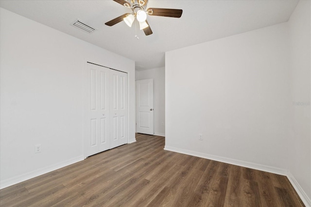 unfurnished bedroom featuring ceiling fan, dark hardwood / wood-style flooring, and a closet