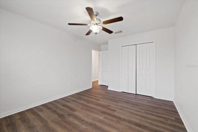 unfurnished bedroom featuring dark hardwood / wood-style flooring, ceiling fan, and a closet