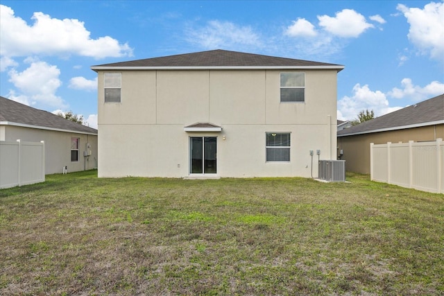 rear view of house with central air condition unit and a lawn