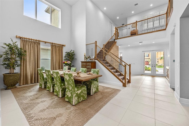 foyer with french doors, a towering ceiling, plenty of natural light, and light tile patterned floors