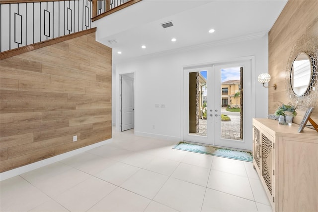 tiled entryway featuring wooden walls, ornamental molding, and french doors