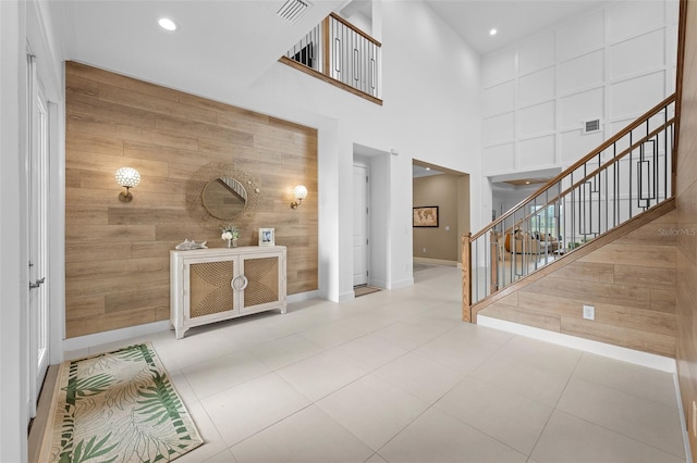 foyer entrance featuring a towering ceiling and wood walls