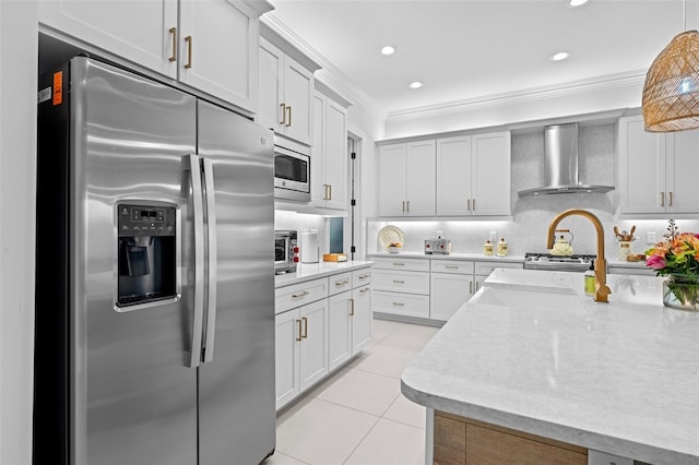 kitchen with light tile patterned floors, ornamental molding, appliances with stainless steel finishes, pendant lighting, and wall chimney range hood