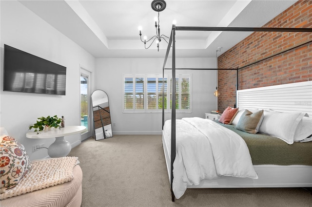 bedroom with a tray ceiling, light colored carpet, and brick wall