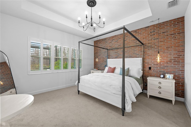 carpeted bedroom featuring a notable chandelier, a tray ceiling, and brick wall