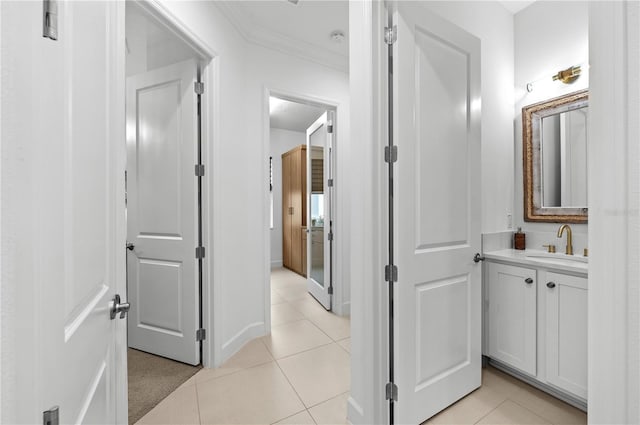 hall with crown molding, sink, and light tile patterned floors