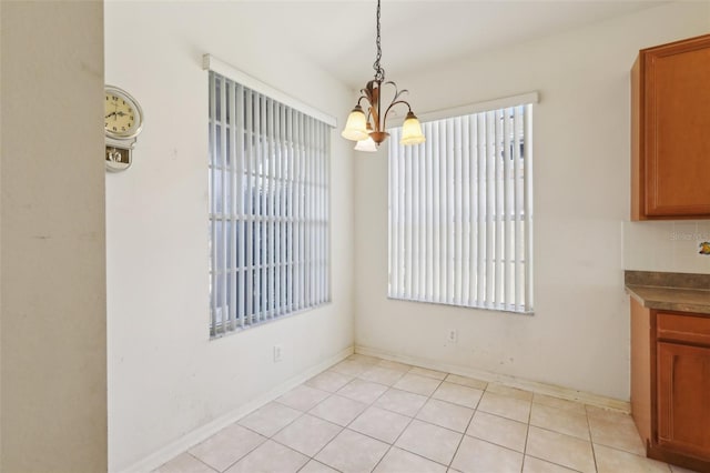 unfurnished dining area featuring light tile patterned floors and a notable chandelier