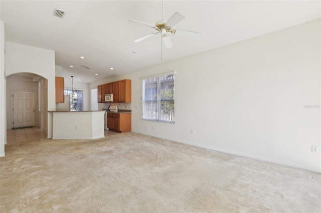 unfurnished living room featuring a wealth of natural light, ceiling fan, and light colored carpet