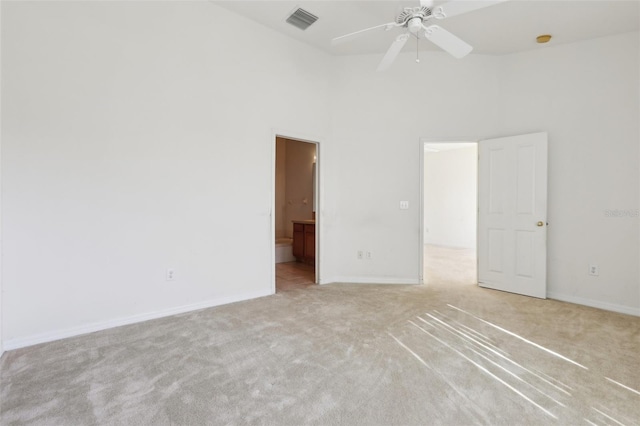 carpeted spare room with ceiling fan and a high ceiling