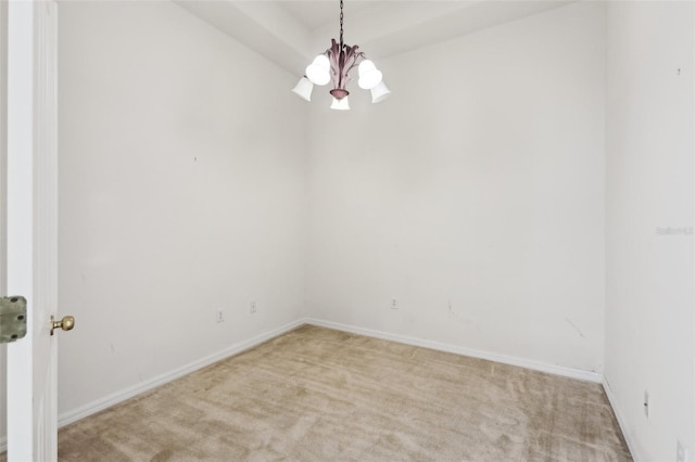 carpeted spare room with a chandelier