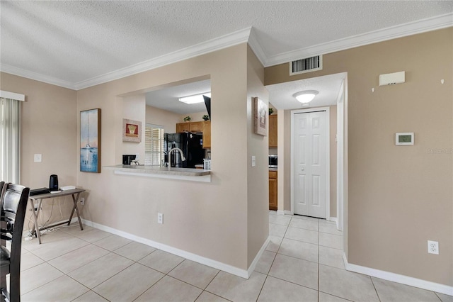 foyer with crown molding, light tile patterned floors, and a textured ceiling