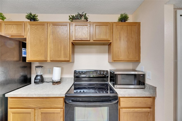 kitchen featuring black appliances, a textured ceiling, and light brown cabinetry