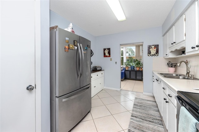 kitchen featuring stainless steel fridge, sink, white cabinets, and a textured ceiling