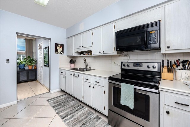 kitchen with electric range, white cabinetry, sink, and light tile patterned floors